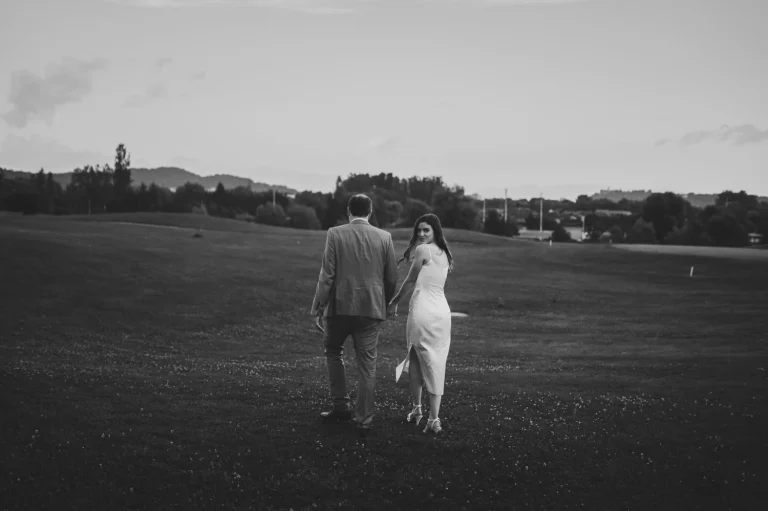 a newlywed couple walking away from the photographer and bride looking back at the photographer